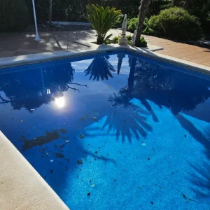 Piscina en El Vendrell con hojas secas en el fondo que requiere limpieza